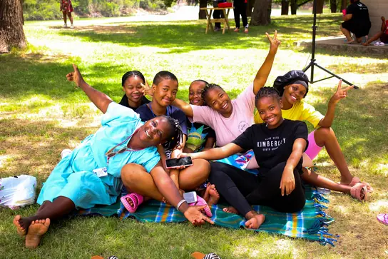 Friends laughing together on a picnic blanket on the grass