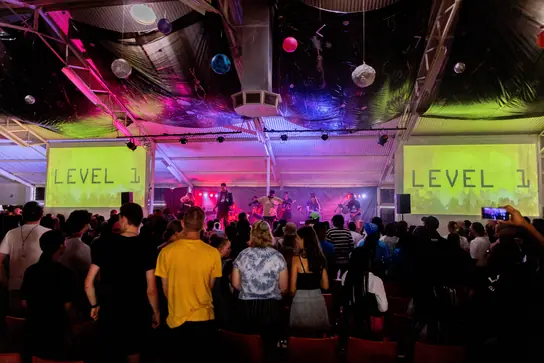 A band on stage under the Level 1 lights with the crowd in front