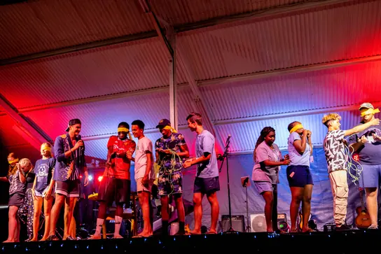 Campers performing together on a lit stage